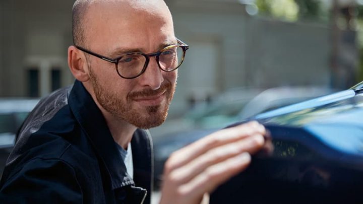 A man looking at an acceptable scuff or scratch on his BMW.