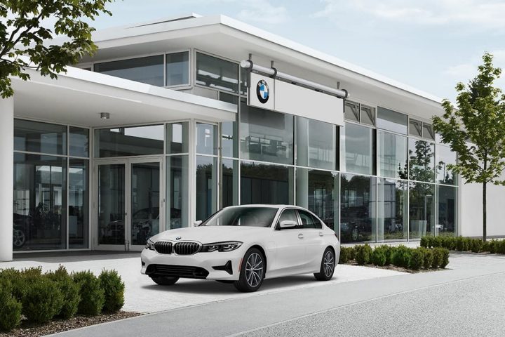 The BMW 330i parked in front of a BMW Center.