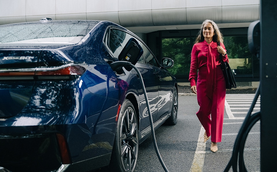Woman beside a EV BMW that's charging 