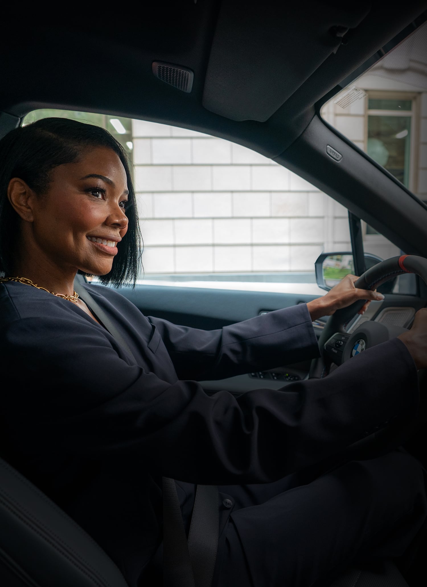A shot from the passenger's seat of Gabrielle Union smiling while driving the BMW iX