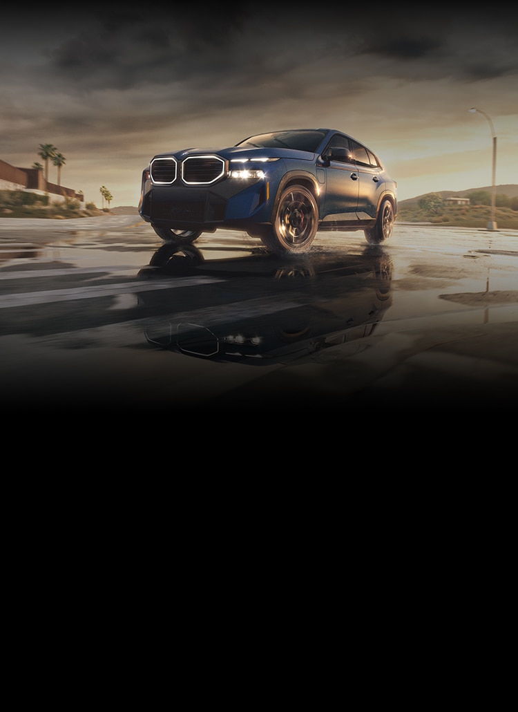 A dramatic shot of the 2026 BMW XM Label moving through an urban desert landscape