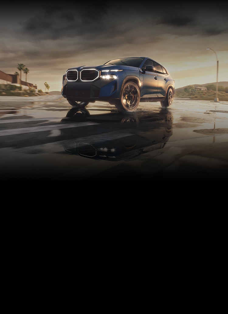 A dramatic shot of the 2026 BMW XM Label moving through an urban desert landscape