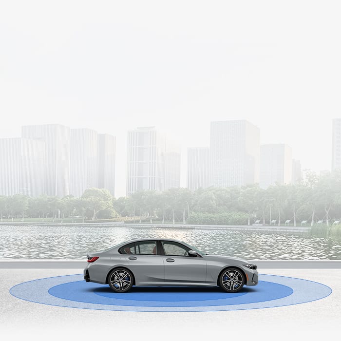 Side profile of the 2024 BMW 3 Series Sedan atop blue circles conveying the sedan's safety technology. A faded cityscape is in the background.