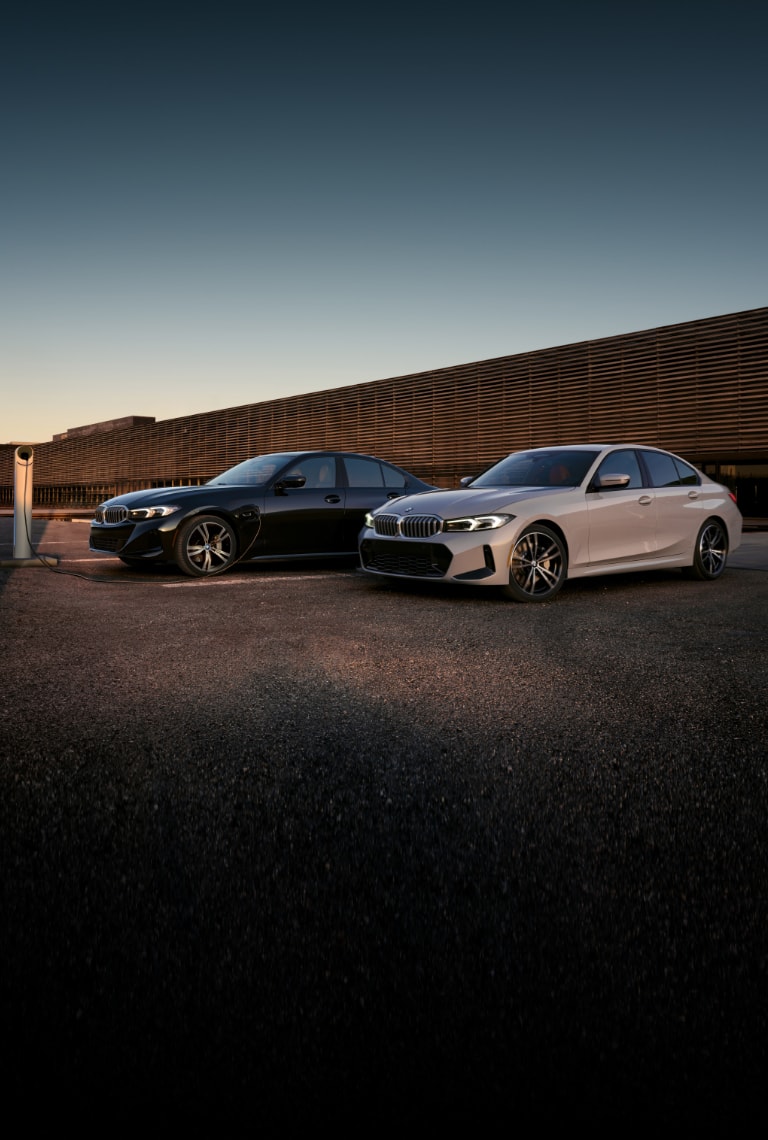 Two 2024 BMW 3 Series Sedans parked  next to each other at dusk