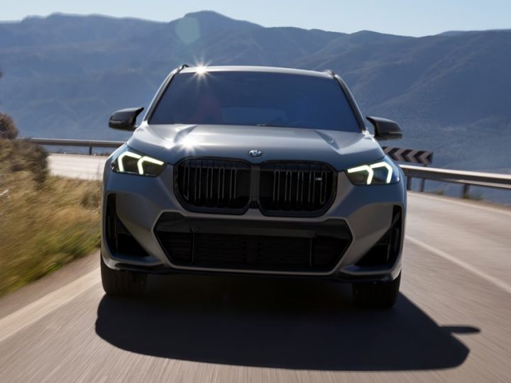 Front view of the X1 M35i SUV driving along highway with river and hills in background