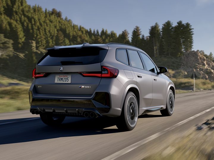 The BMW X1 M35i SUV accelerates down a highway with trees blurred in background