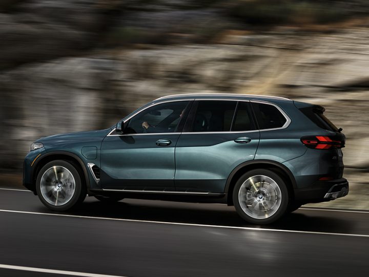 A 2025 BMW X5 xDrive50e driving along a rocky cliffside