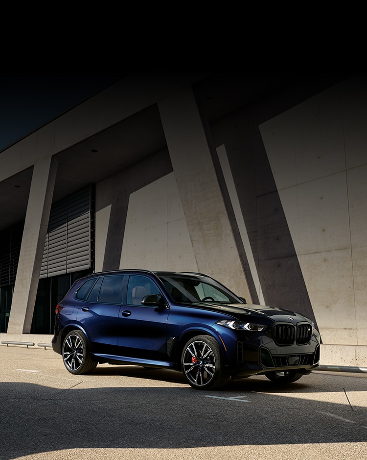 2025 BMW X5 M60i parked in front of a concrete building