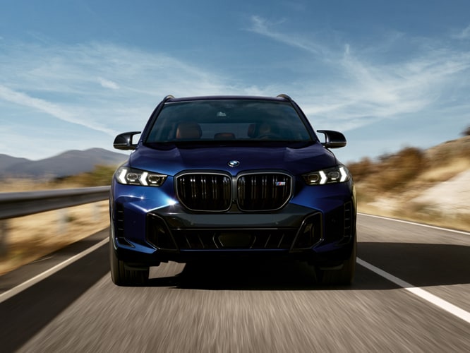 Front view of a charging BMW X5 M60i on a straight road