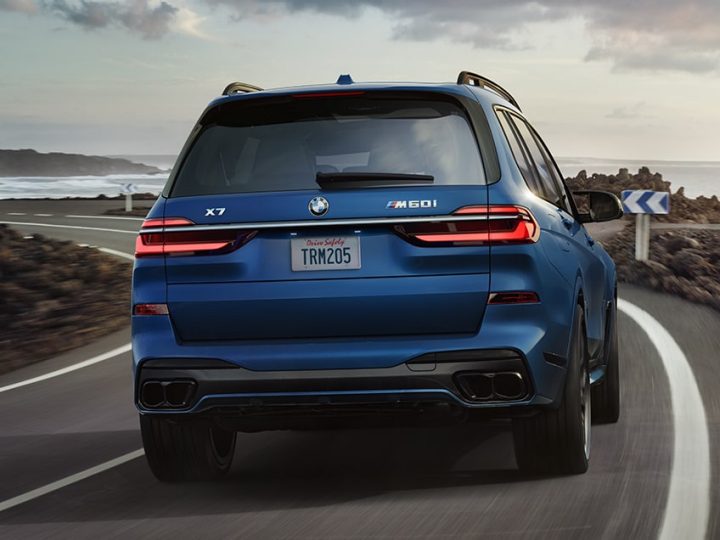 Rear shot of the 2025 BMW X7 M60i driving on a road 