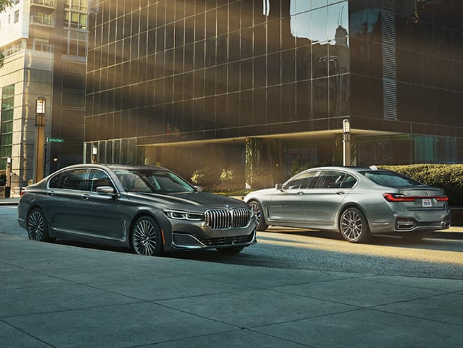 Two BMWs parked side by side under glass building