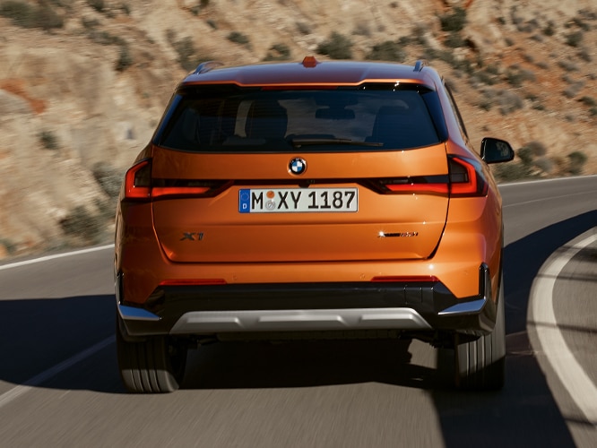 Back view of the full LED headlights and sporty rear spoiler on the 2023 BMW X1 in a mountainous setting