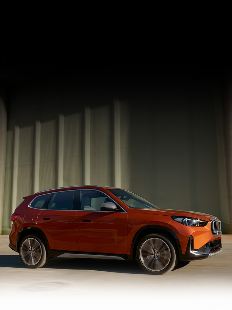 Dynamic side profile shot of the 2023 BMW X1 in Utah Orange Metallic on the move