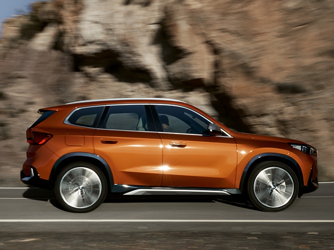 Dynamic side profile shot of the BMW X1 featuring its longer wheelbase, integrated door handles, and rugged body
