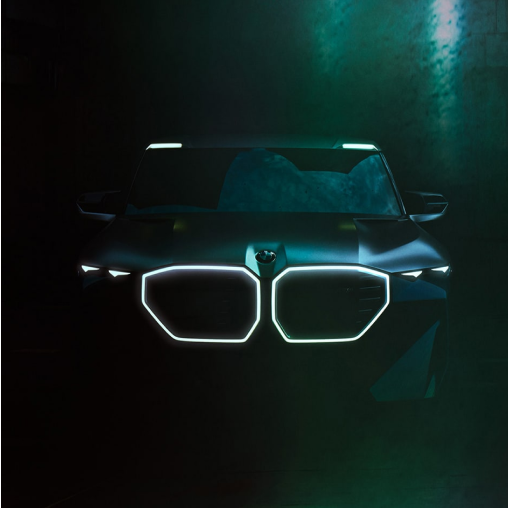 Front of a BMW M vehicle parked in the dark with its kidney grille aglow