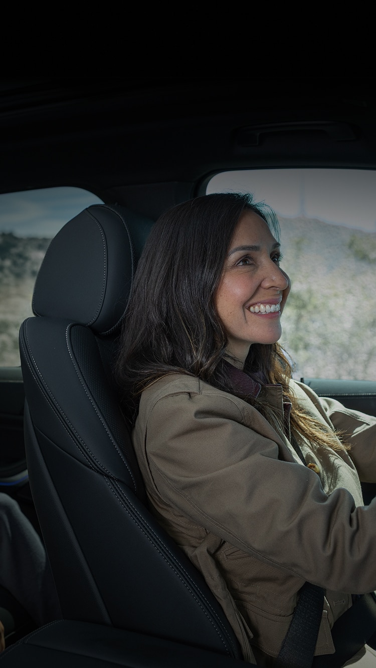 A mom smiles back in the mirror at her son in the backseat of her BMW SUV