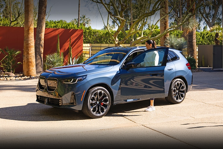 Ana Ivanović gets into a BMW X3 M50 xDrive, which is parked in a desert driveway on a sunny day