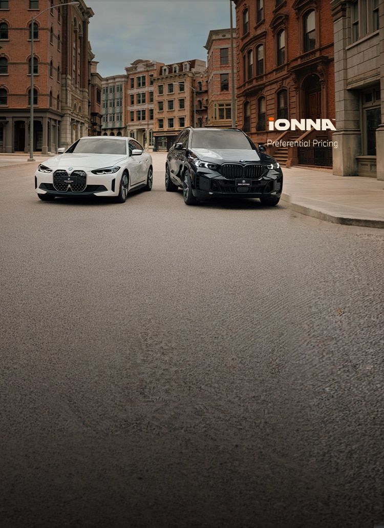 A BMW i4 and X5 xDrive50e sit parked in a city street lined with brownstone and brick buildings. The IONNA preferential pricing logo sits on the right side of the image.