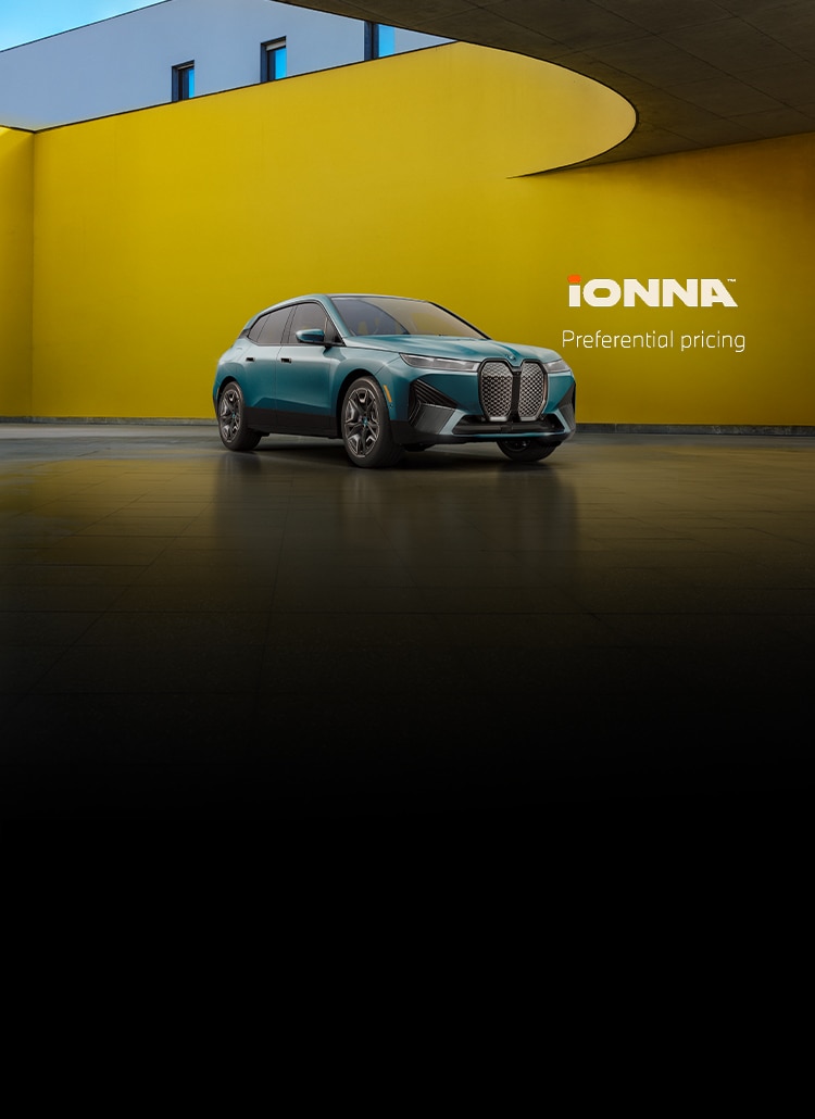 Angled view of a parked BMW iX xDrive50 in a sleek space with a curved yellow wall.