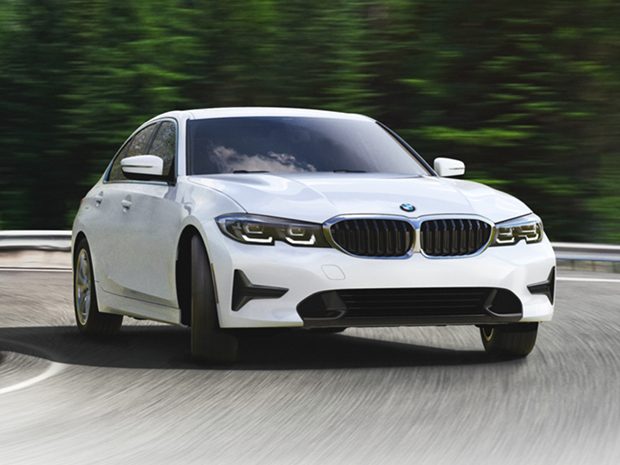 2022 BMW 330e plug-in hybrid rounding the corner on a road surrounded by trees