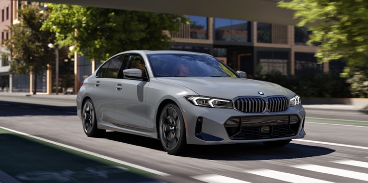A BMW 3 Series Sedan driving on a tree-lined city street