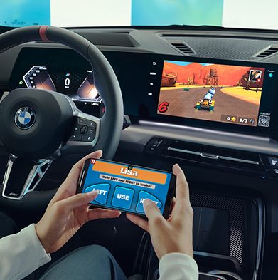 An over-the-shoulder shot of a woman playing video games on her BMW screen using her phone as a controller