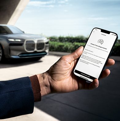 Image of a person's hand holding a smartphone showcasing the MyBMW app