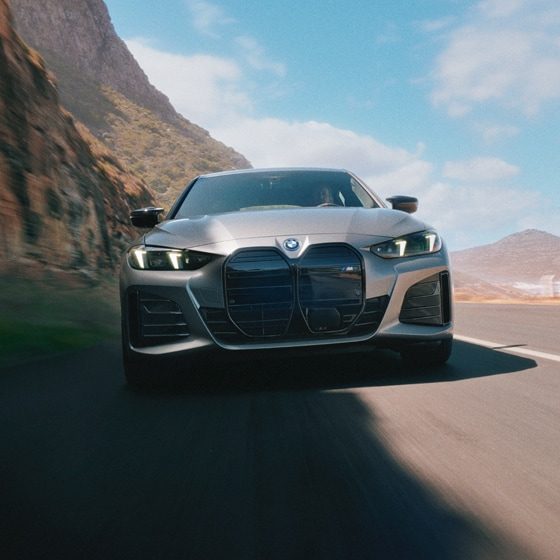 Cinematic image of a BMW driving past a cityscape during a colorful sunset