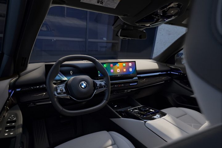 Interior image of BMW cockpit showing steering wheel, display, and gears