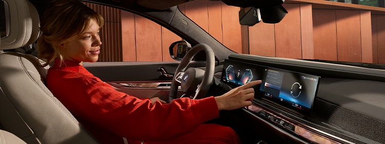 A driver uses the Curved Display to interact with the iDrive system in their BMW