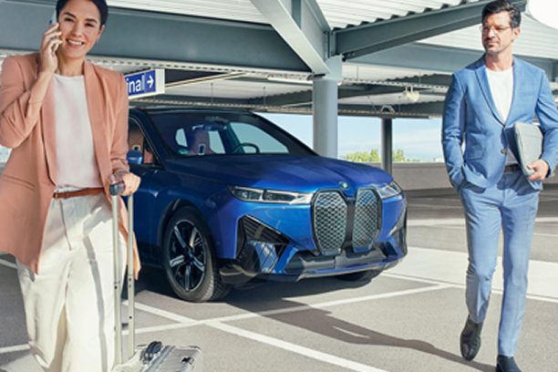 A couple in business attire walk away from their BMW in a parking garage