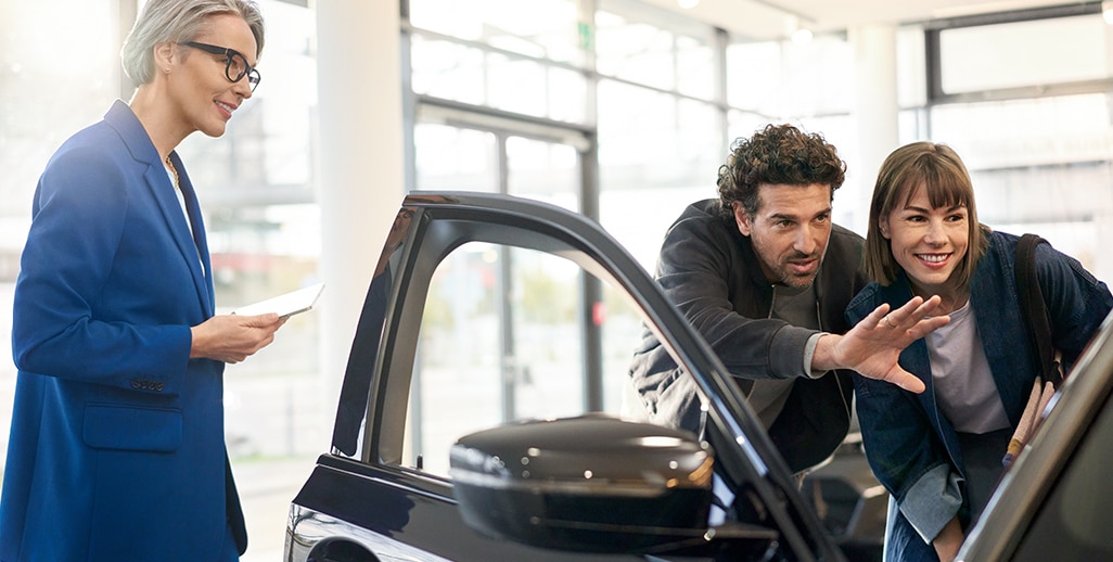 A couple in business attire looking into a BMW at a dealership