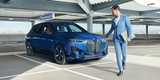 A BMW driver walks away from his BMW in a garage, using the key fob to lock it