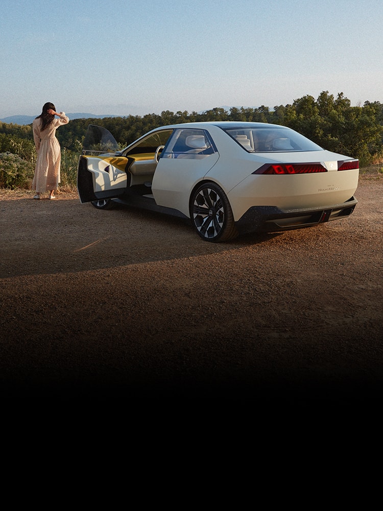 A woman takes in a beautiful view after parking her BMW Neue Klasse Sedan at a scenic overlook