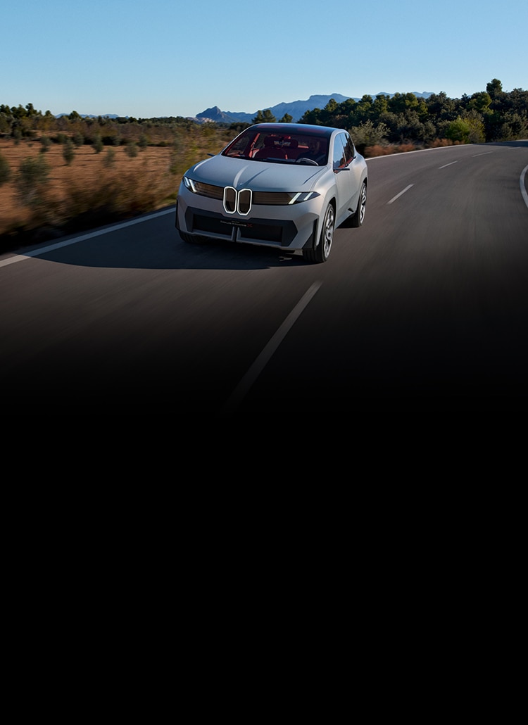 Dynamic shot of the BMW Neue Klasse X SUV accelerating down a rural highway