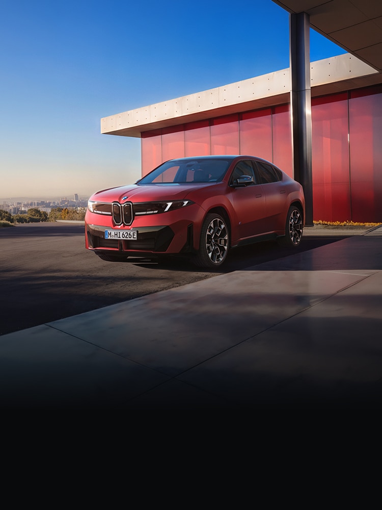 The BMW iX4 parked in front of a modern red building