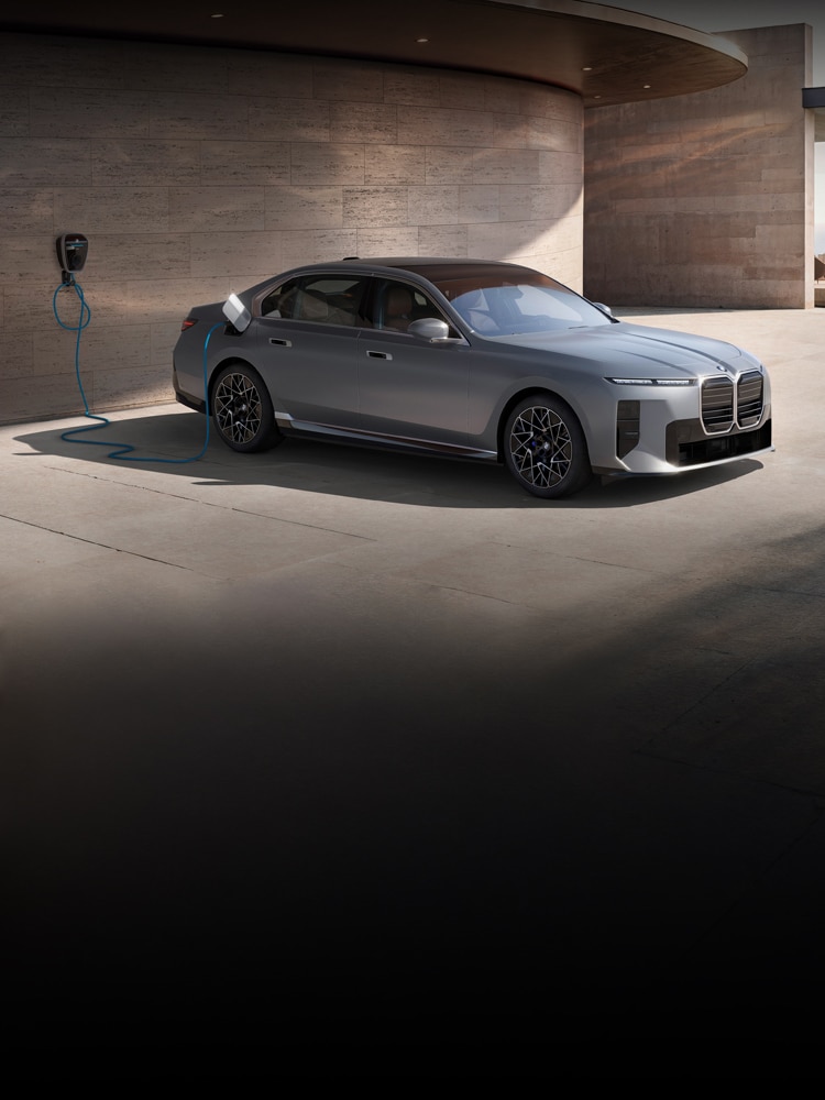 Dramatic side view of the 2027 BMW i7 Sedan charging while parked in a stately, modern home parking area