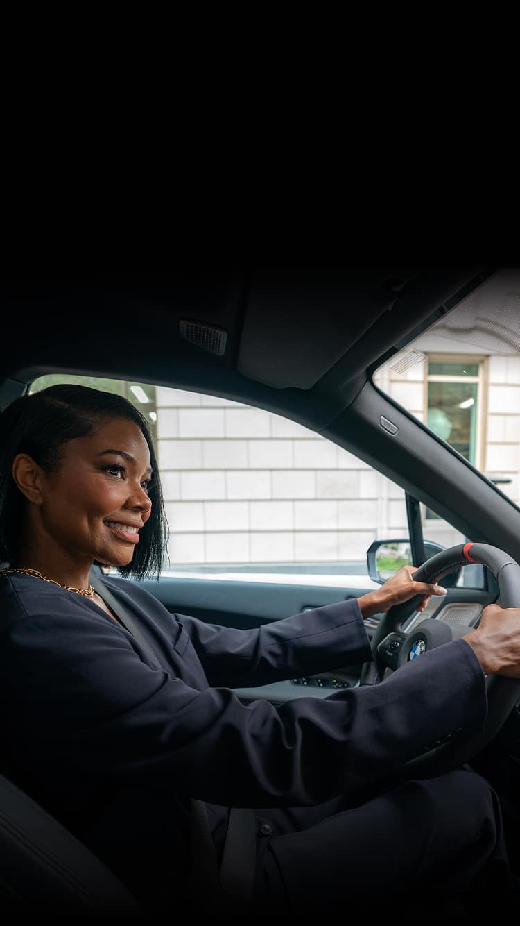 A shot from the passenger's seat of Gabrielle Union smiling while driving the BMW iX