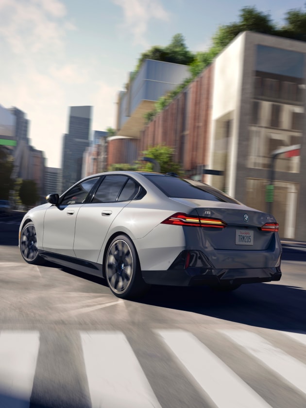 Dynamic shot of the 2024 BMW i5 eDrive40 turning left at an urban intersection