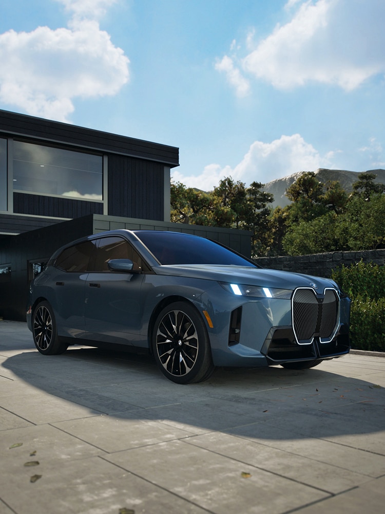 A BMW iX parked in the driveway of a modern looking home