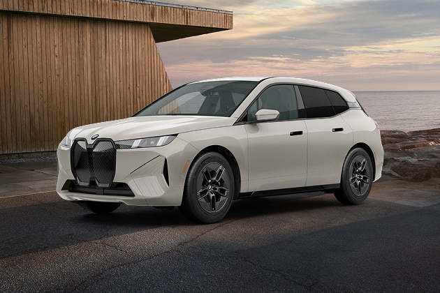 The BMW iX xDrive45 parked next to a modern building on a rocky coastline