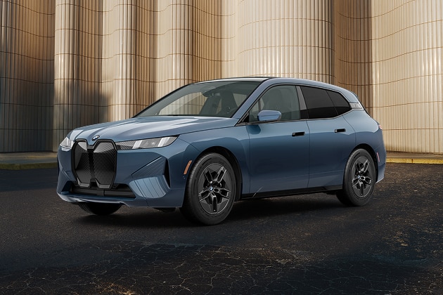 The BMW iX xDrive60 parked next to a tall rippled wall.