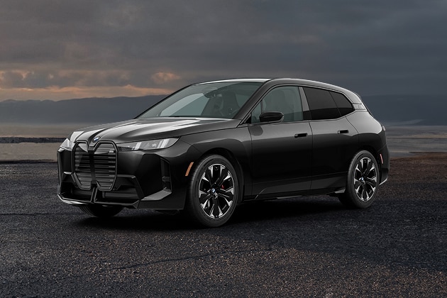The BMW iX M70 parked next to a sweeping coastline.