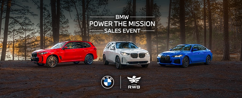 Three BMWs parked side-by-side in a rustic, wooded setting with a serene lake in the background