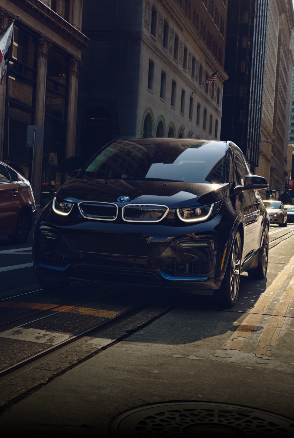 Head-on shot of the BMW i3s Electric Sedan driving through a city