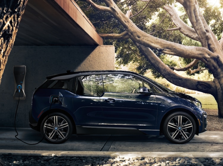 Side profile shot of a parked BMW i3 Electric Sedan parked near a tree