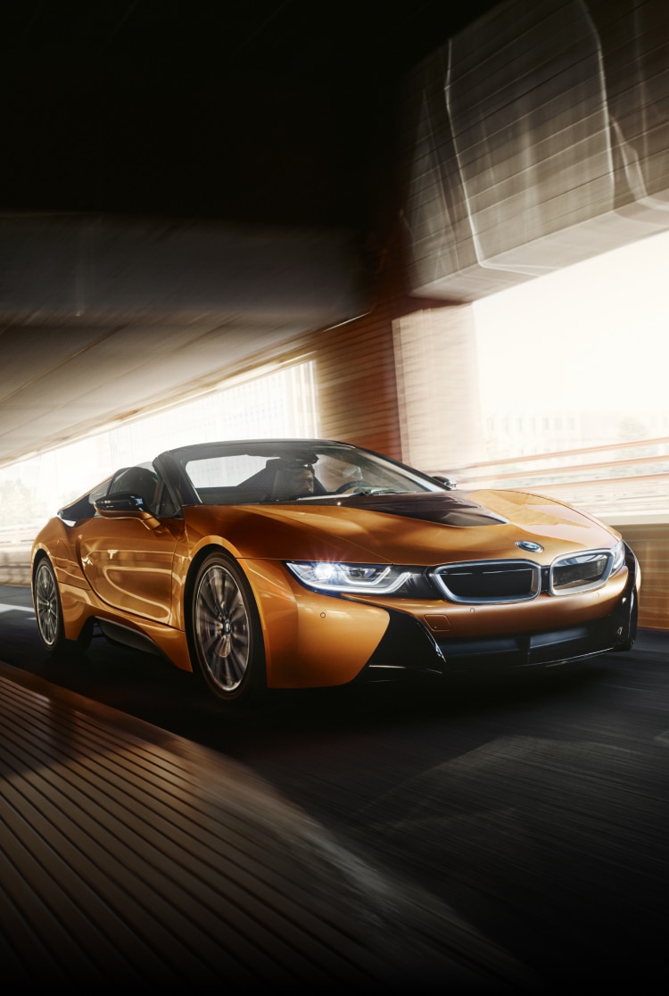 Dynamic shot of the BMW i8 Roadster driving through a tunnel with headlights aglow
