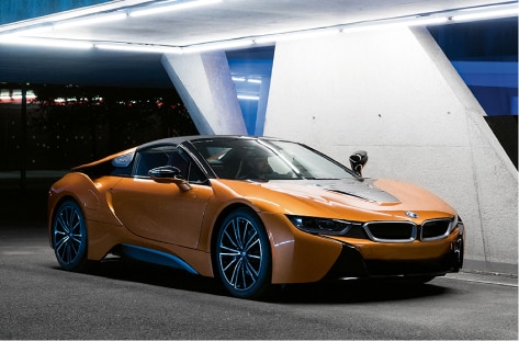 Side shot of the BMW i8 Roadster closing its electric top while parked in front of a city skyline