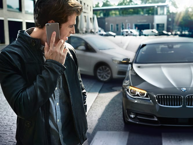 BMW driver on his phone reporting the car accident that has occurred to his BMW