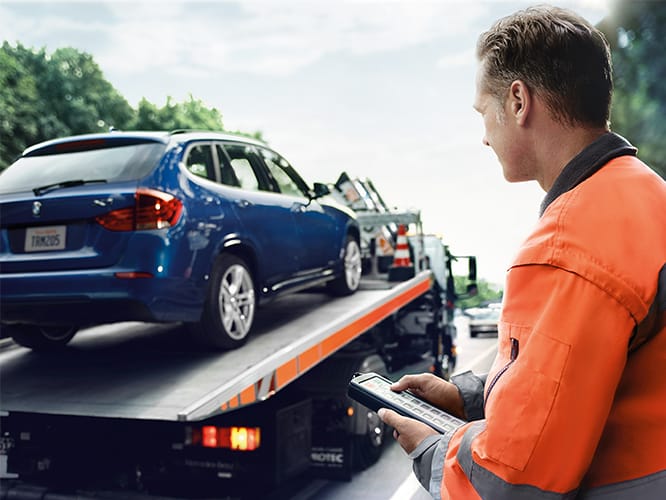 A towing service picks up a BMW on the side of the road